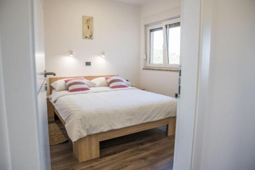 a bedroom with a bed with white sheets and red pillows at Apartmani Petra i Tea in Krapina