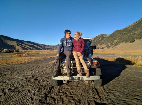 two people sitting on the back of a truck in the desert at INNI Homestay in Malang