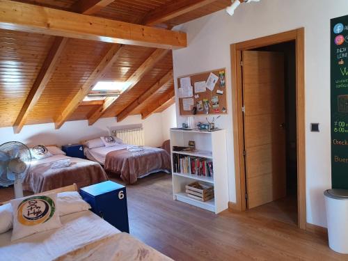 2 łóżka w pokoju z drewnianym sufitem w obiekcie Albergue Só Por Hoje , Albergue de Peregrinos del Caminho de Santiago w mieście Astorga