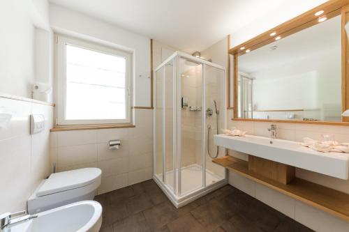 a bathroom with a toilet and a shower and a sink at Hotel Lärchenhof in Solda
