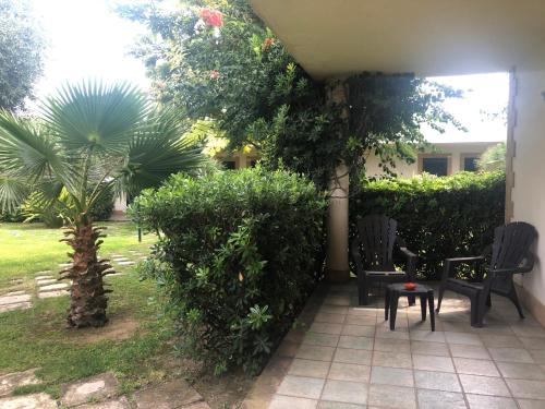 a patio with chairs and a table and trees at Valle di Mare Country Resort in Fontane Bianche