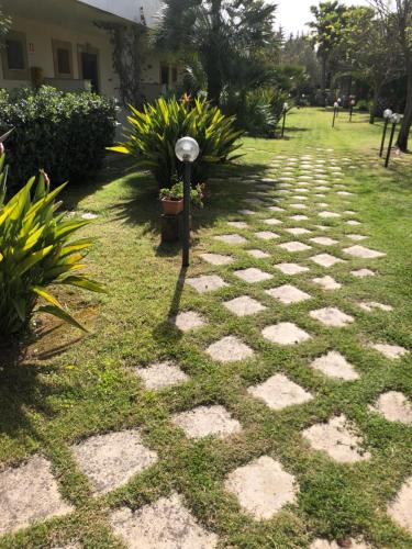 a stone walkway with plants and a lamp in the grass at Valle di Mare Country Resort in Fontane Bianche
