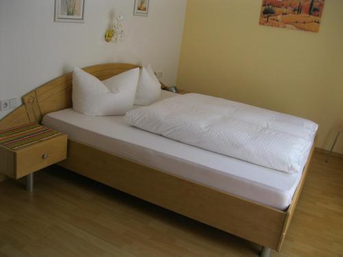 un lit avec des draps blancs et des oreillers dans une chambre dans l'établissement Appartement Geisler, à Zell am Ziller