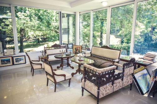 a living room filled with furniture and large windows at Vila Mila in Arandjelovac