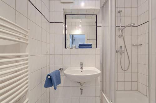 a white bathroom with a sink and a shower at Am Ostseestrand 1 in Zingst