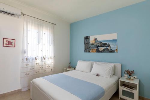 um quarto com uma cama branca e uma parede azul em House Myrtos em Lacónia