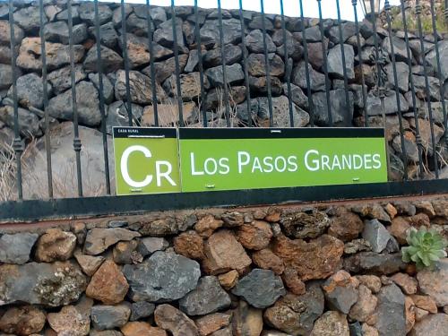 a green sign on a rock wall with a sign at Casa Rural Los Pasos Grandes in Isora