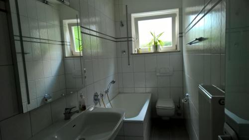 een badkamer met een bad, een wastafel en een toilet bij Ferienwohnung am Brasselsberg in Kassel