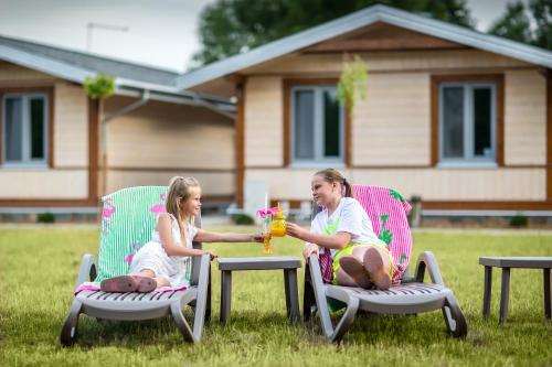 two girls sitting in lawn chairs with drinks at Bliżej Natury in Białowieża