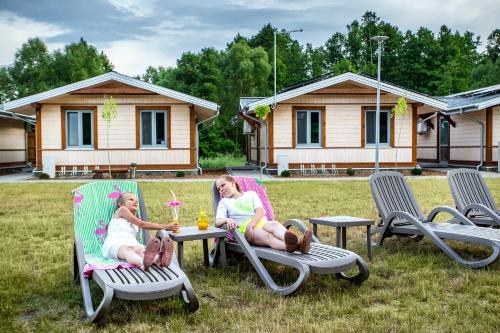 two girls sitting in lawn chairs in a yard at Bliżej Natury in Białowieża