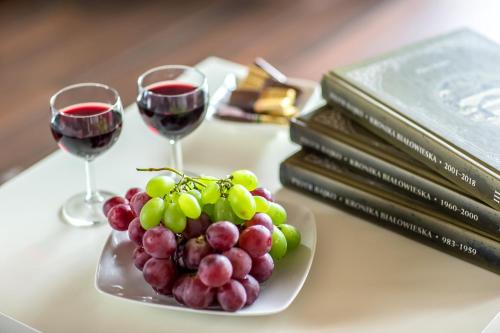a plate of grapes and two glasses of wine on a table at Bliżej Natury in Białowieża