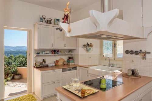 a kitchen with white cabinets and a sink and a window at Irida's House, a fairylike house with supurb view in Korakiaí