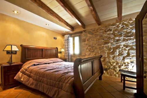 a bedroom with a bed and a stone wall at Villa Can Bassa Muro in Muro