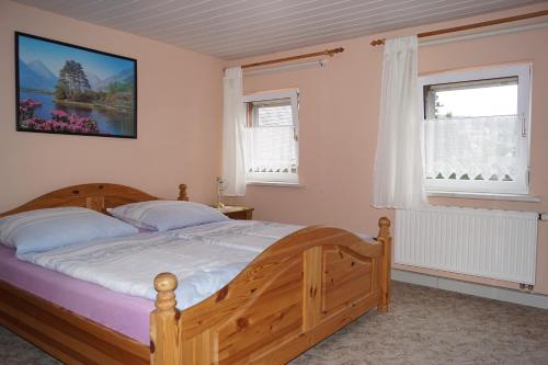 a bedroom with a wooden bed and two windows at Ferienwohnung Familie Arlt in Königstein an der Elbe
