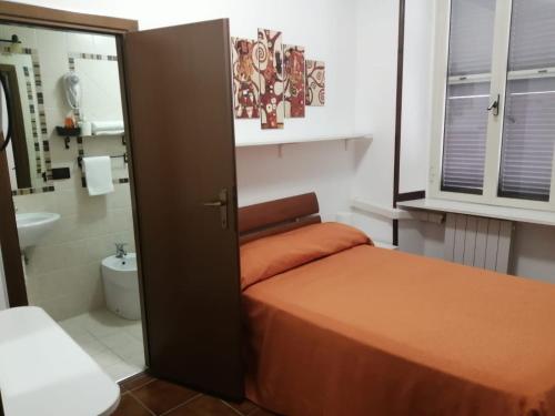 a small bedroom with a bed and a bathroom at Albergo Ollolai in Civitavecchia