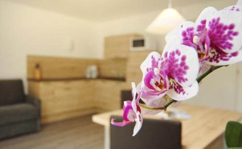 um vaso com flores roxas e brancas numa sala de estar em Appartment Charly em Siusi