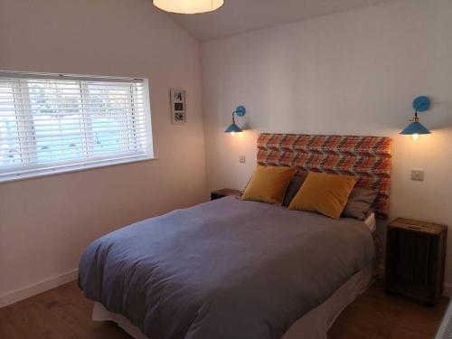 a bedroom with a large bed with two yellow pillows at The Bird House at Woodburn Cottage in Dedham