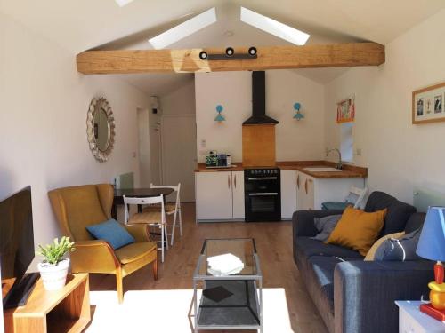 a living room with a blue couch and a kitchen at The Bird House at Woodburn Cottage in Dedham