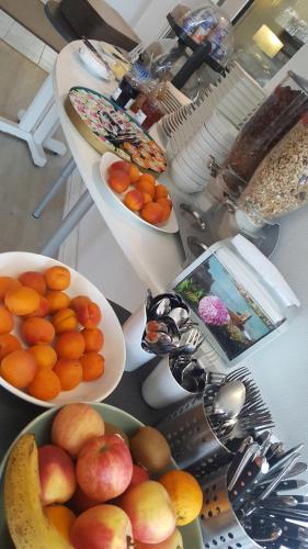 une table avec des coupes de fruits, des cuillères et des assiettes de nourriture dans l'établissement L'annexe de l'Hôtel de l'Europe, à Perros-Guirec