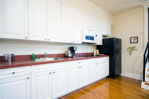 a kitchen with white cabinets and a black refrigerator at The Box House Hotel in Brooklyn