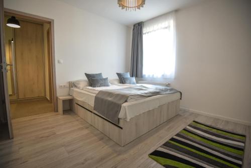 a bedroom with a bed with a window and a rug at Francesca Apartman in Siófok