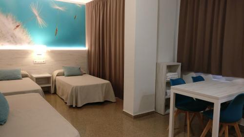 Habitación de hotel con cama, mesa y sillas en Aparthotel Las Mariposas en Lloret de Mar