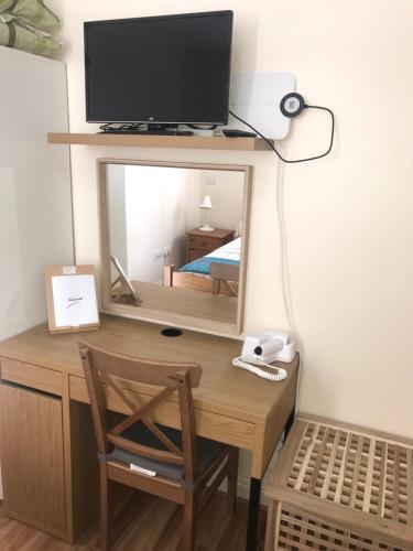 a desk with a mirror and a television on top of it at Chatsworth Guest House in London