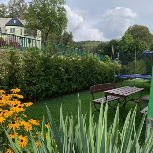 a picnic table and bench in a garden with flowers at Ferienwohnung Herold in Olbernhau