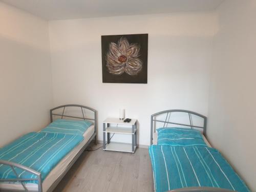 2 camas en una habitación con una mesa y una foto en Wohnung, Zimmer in Frankfurt Flughafen zu vermieten en Mörfelden-Walldorf