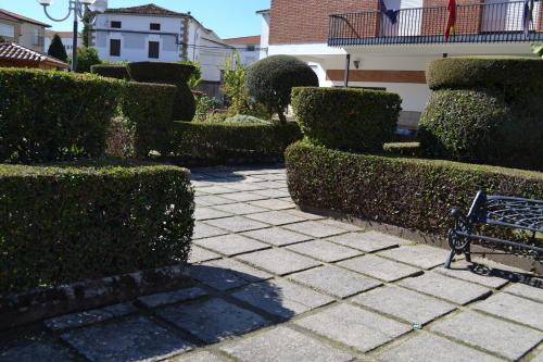 a bench sitting on a sidewalk next to some bushes at Hostal Vadillo in Losar de la Vera