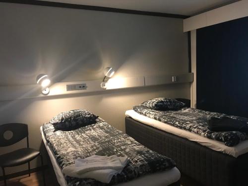 2 camas en una habitación con luces en la pared en Hotelli Kolari, en Kolari