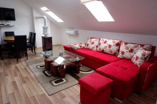 a living room with a red couch and a table at Hotel Kings Apartments in Kolgecaj