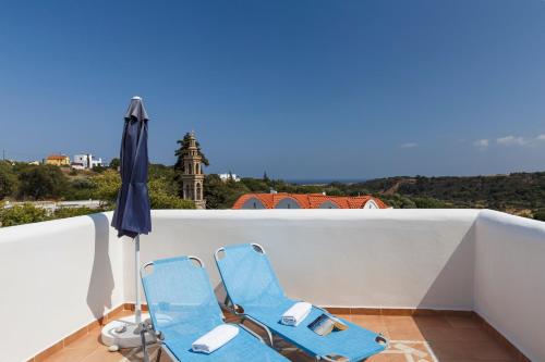 two blue chairs and an umbrella on a balcony at House Salvia in Lachania