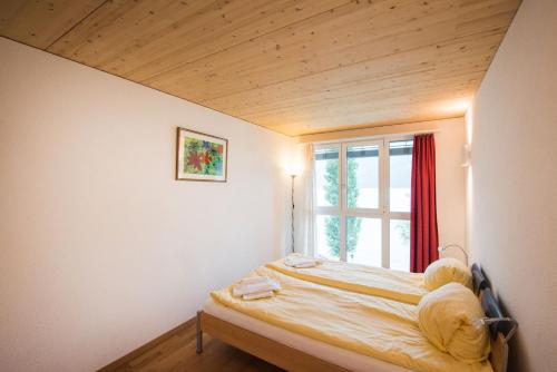 Bett in einem Zimmer mit Fenster in der Unterkunft Beaulac Penthouse in Brienz