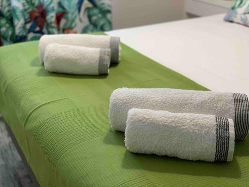 three rolled towels on a green blanket on a bed at APARTAMENTO ALEGRIA CENTRO in Albacete