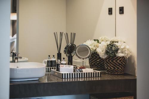 a bathroom counter with a sink and flowers and a mirror at Casal dos Capelinhos - Douro in Santa Marta de Penaguião