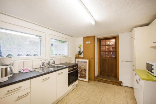uma cozinha com armários brancos, um lavatório e uma janela em Francy em Brienz