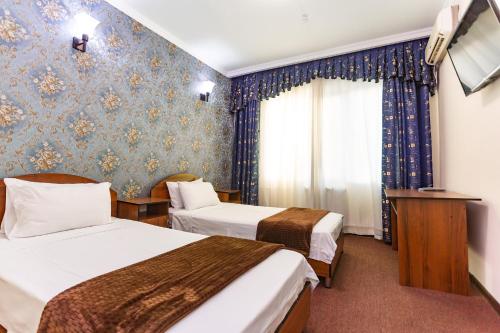 a hotel room with two beds and a window at Asson Hotel Termez in Termiz
