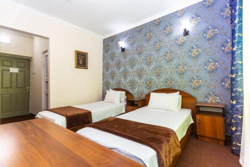 a hotel room with two beds and a blue wall at Asson Hotel Termez in Termiz