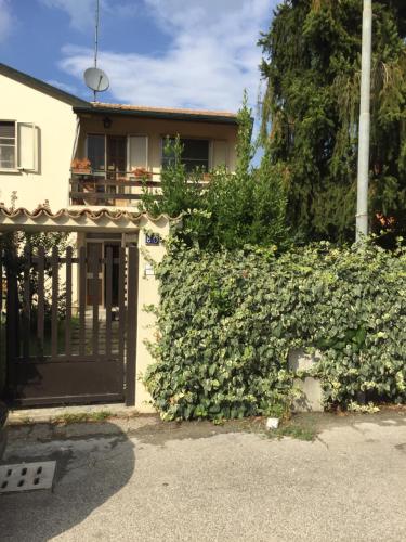 a house with a gate and a hedge with flowers at Casa Matì in Altedo