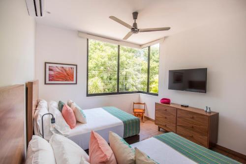 1 dormitorio con 2 camas, TV y ventana en Tannah Luxury Rentals, en Mérida