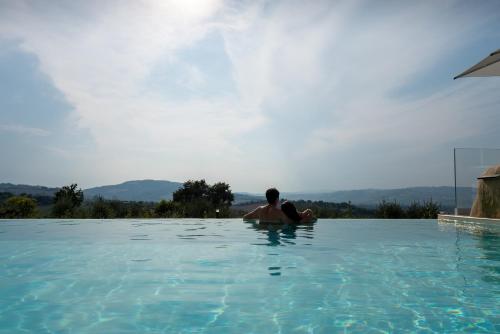a man sitting in the water in a swimming pool at La Maggiolina Country House in Montelabbate
