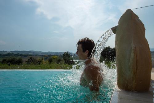 a man is in the water in a pool at La Maggiolina Country House in Montelabbate