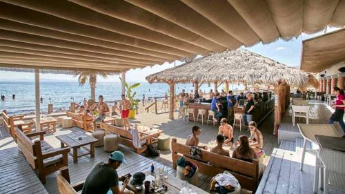 a group of people sitting at a beach restaurant at Your Holiday House in Porto Rafti