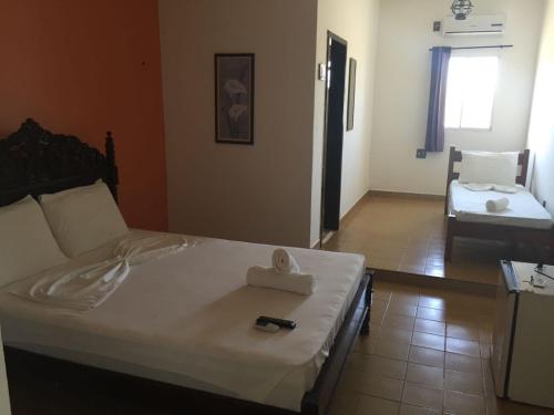 um quarto com uma cama com um controlo remoto em Beach Hotel Jacuma em Jacumã