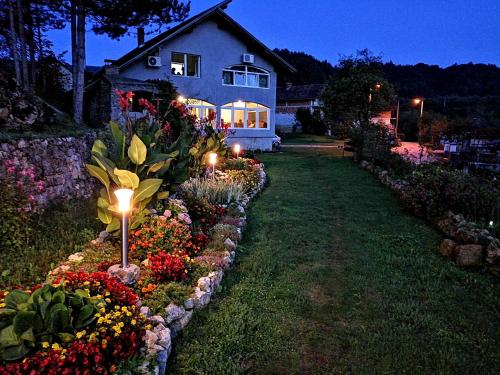 a garden with flowers and lights in front of a house at Unaqua Apartments in Kulen Vakuf