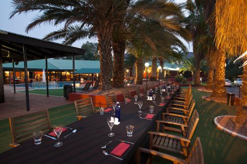a long table with wine glasses and wooden chairs at Mercure Alice Springs Resort in Alice Springs