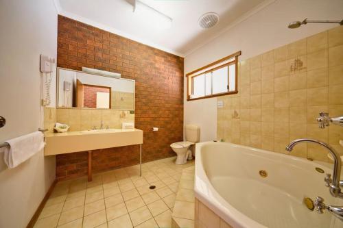 a bathroom with a tub and a sink and a toilet at Paradise Lakes Motel Shepparton in Shepparton