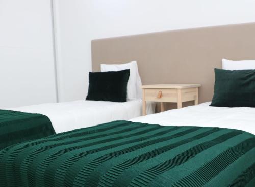 2 Betten mit grüner und weißer Bettwäsche in einem Zimmer in der Unterkunft COLD CITY HOUSE in Guarda