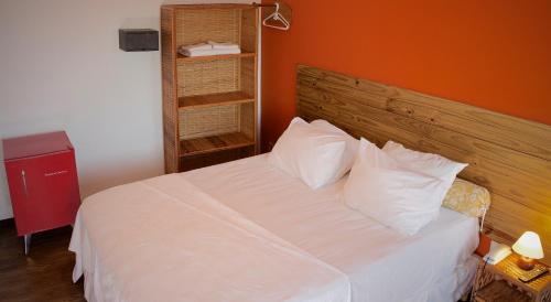 a bedroom with a white bed with an orange wall at Pousada Stella Tropical in Salvador